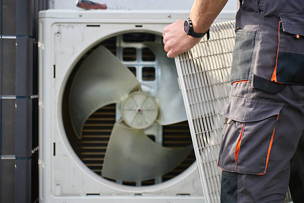 HVAC technician removing the fan grille from an outdoor heat pump